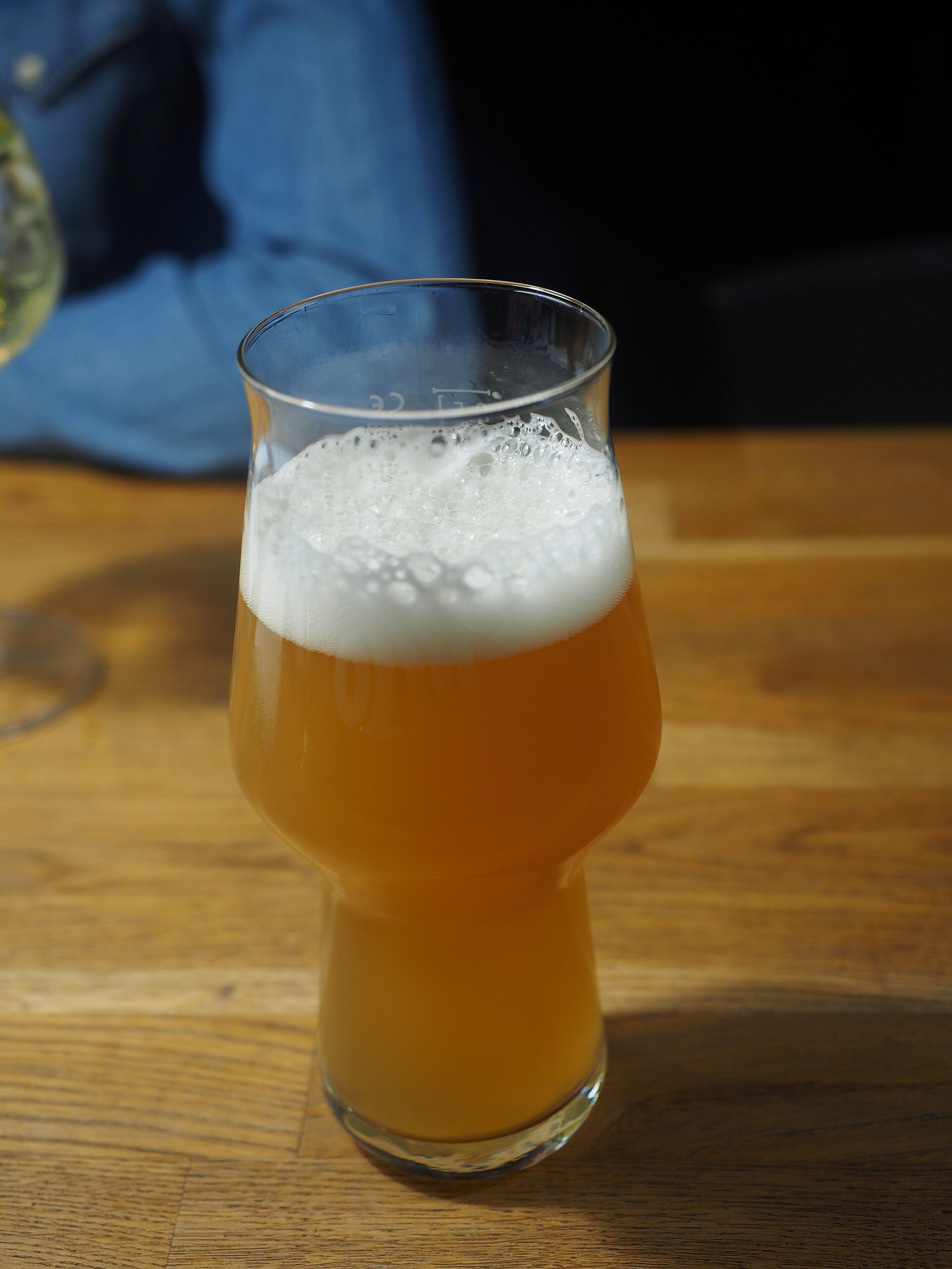 木のテーブルに置かれた泡の立つビールのグラス