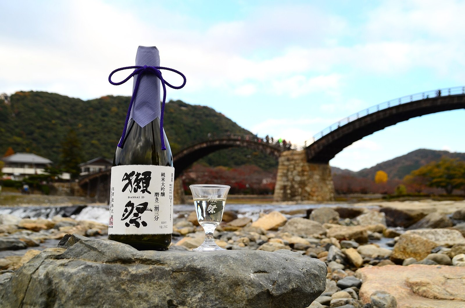 錦帯橋を背にした獺祭 純米大吟醸 磨き二割三分の瓶と杯