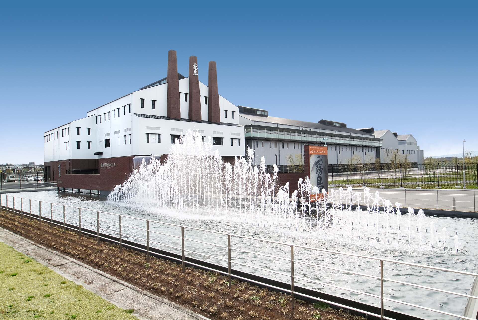 噴水の奥に建つ霧島酒造の本社増設工場